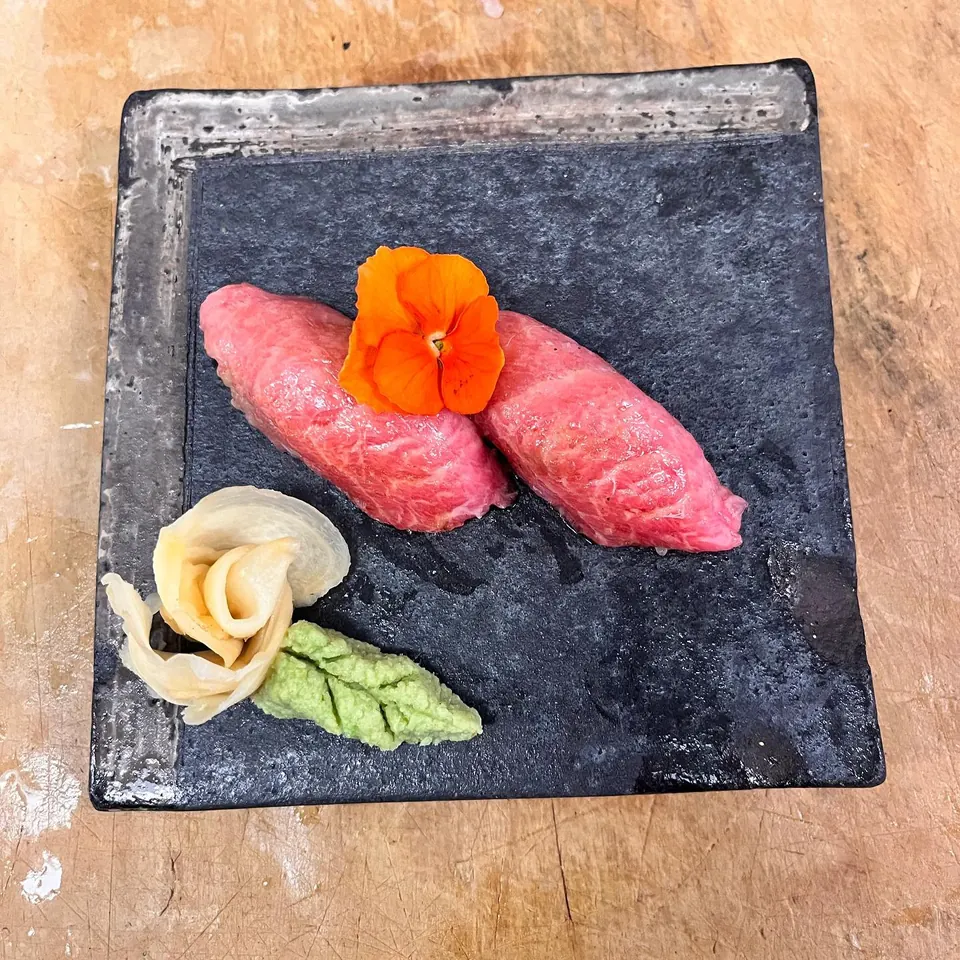 Two pieces of chutoro nigiri on a slate, from one of Mica's omakase dinners